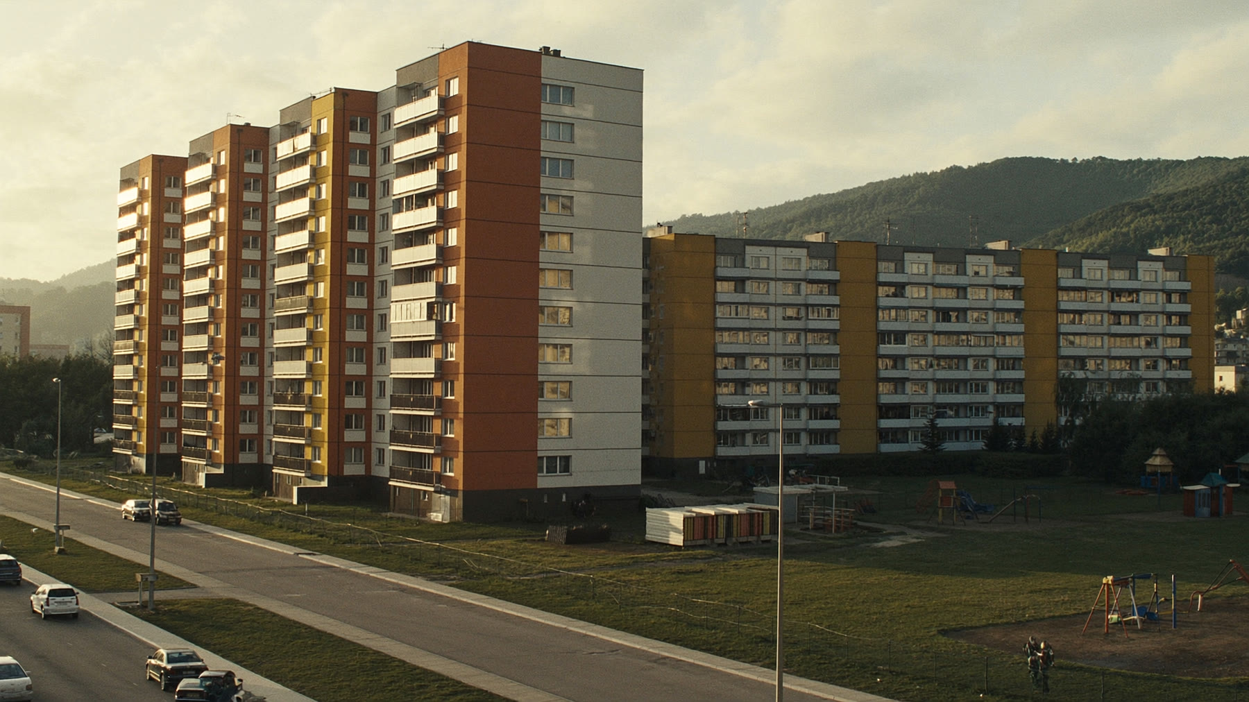 Panelové sídlisko v podvečernom svetle s kopcami v pozadí
